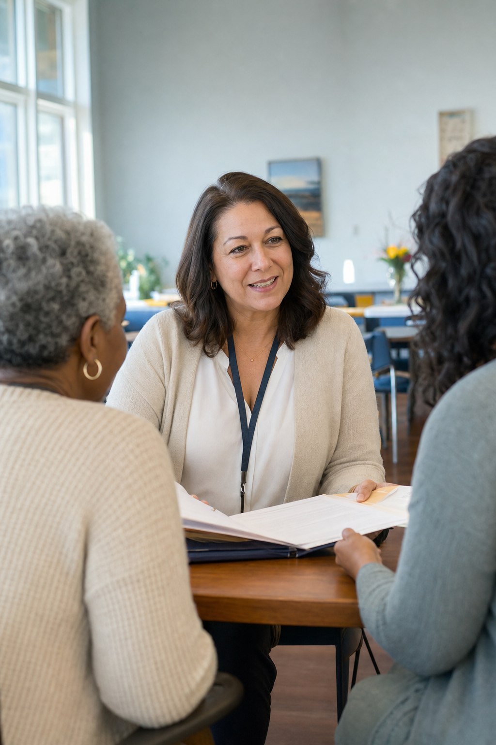 An experienced Beatrice Loving Heart care coordinator talks warmly with an older client and a family member in a bright community room.